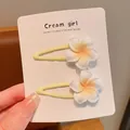Detail view of two sweet white frangipani flower hair clips on a display card. - Large Frangipani BB Clip
