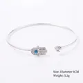 Silver-colored open bangle featuring a crystal-encrusted Hamsa hand and blue stone. - Style 7 Silver