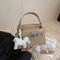 Elegante beige Kelly-Tasche mit Krokoprägung und einem weißen Pegasus-Anhänger - Ohne Anhänger / Khaki