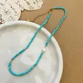 Turquoise beaded necklace with a white pearl and gold accents on a ceramic plate - Turquoise Artificial Pearl