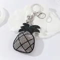 Close-up of cute pineapple keychain with sparkling rhinestones and silver hardware - White