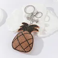 Detail view of a cute pineapple keychain with sparkling rhinestones and silver bells. - Champagne