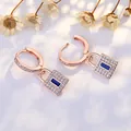 Elegant rose gold hoop earrings with crystal pavé lock charms and blue stone accent. - Rose Gold