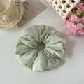 Vista dettagliata di un elastico per capelli in tessuto verde chiaro con decorazioni - Verde