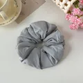 Macro detail of a grey oversized fabric scrunchie showing the soft pleated fabric texture. - Gray