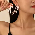 Elegante vintage roze lint strik oorbellen met zoete emaille afwerking op model oor - Roze Strik (7383)