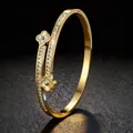 Elegante goudkleurige klaver armband met fonkelende kristallen en wit inlegwerk detail - Goud
