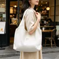 Modella con una grande borsa tote bianca a pois in un ambiente urbano informale. - Bianco Sporco a Pois