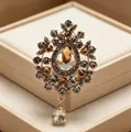 Primo piano della spilla in stile vintage con cristalli ambrati e pendente. - Champagne