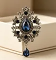 Dettaglio ravvicinato di spilla stile palazzo vintage con cristalli blu a goccia. - Blu