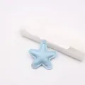 Close-up detail of a light blue padded faux leather star pendant with white stitching. - Star Accessories / Pearlescent Sky Blue