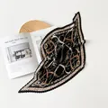 Dettaglio di un foulard in seta nera a pieghe con elegante stampa a catena d'oro - 70cm / Cinturino in Pelle Nera