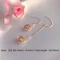 Detailed macro view of asymmetric gold drop earrings with pearls and zircon cages - Natural Pearl / Asymmetric Hollow Ball Artificial Pearl Style (EH66--2)