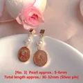 Close-up of elegant freshwater pearl and gold coin earrings on a white plate - Natural Pearl / Gold Coin Single Artificial Pearl Style (EH66--No. 3)