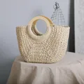 Close-up of vintage straw bag featuring round wooden handles and weave texture - White