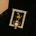 Elegant golden frame brooch featuring a decorative vase and yellow dried flowers. - KC Gold Picture Frame Arrangement Brooch (3946) / Gold