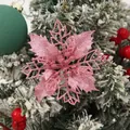 Close-up of a 9cm pink glittery hollow poinsettia flower on a snowy Christmas tree. - Pink