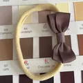 Soft elastic baby headband with brown grosgrain ribbon bow on a color chart background - Coffee