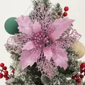 Glittery pink poinsettia Christmas flower ornament on a snowy Christmas tree branch - Rose Gold