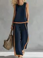 Detail view of sleeveless navy top and wide-leg pants with orange contrast stripes. - S / Navy Blue