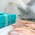 Rose gold knot necklace with diamond accents and elegant gift box background. - Rose Gold Knotted Rope Necklace