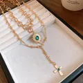 Close-up of vintage gold layered necklace with emerald green stone and cross pendant in tray. - Cross Sunburst Layered Style / Gold