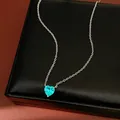 Close-up of vibrant turquoise heart-shaped zircon pendant on a delicate silver chain - Necklace / Green