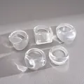 High-quality macro view of five-piece set transparent resin geometric rings on grey leather. - 5 Pieces / White