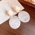 Detail view of the elegant marble-patterned resin oval pendant earrings - White