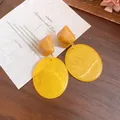 Close-up of vintage resin drop earrings in Maillard yellow with geometric shapes - Yellow