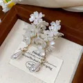Detailed macro shot of French style white flower cluster earrings with pearl tassel drop - Flower Style / White