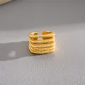 Detalle macro de un lujoso anillo abierto multicapa con textura chapado en oro de 18k - Dorado