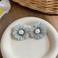 Detailed view of French style fabric flower stud earrings with central white pearls - Cyan