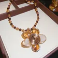 Dettaglio di una collana vintage di perle con ciondolo a fiore avvolto in filo metallico - Marrone