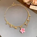 Detailed close-up of a vintage gold chain necklace featuring a pink enamel flower pendant - Necklace - Gold - Pink