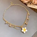 Detail view of a vintage gold chain necklace featuring a white plumeria flower pendant. - Necklace - Gold - White
