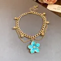 Close-up of a vintage gold-toned anklet featuring a detailed blue flower pendant. - Anklet-Gold-Blue