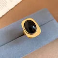 Detailed view of a vintage rectangular gold-tone ring with a black oval stone - Gold-Black