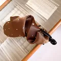 Dettaglio di un fermaglio a banana in raso plissettato marrone con strass scintillanti - Pinza a Banana - Marrone