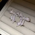 Primer plano de pendientes de lazo con circonitas brillantes en joyero de terciopelo - Estilo Lazo / Pin de Plata S925 / Plateado