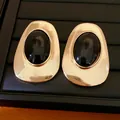 Close-up macro view of vintage gold stud earrings featuring polished oval black stones - Irregular Oval Studs / Gold Black