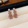 Nahaufnahme von eleganten rosa Bärenohrringen mit glitzernden Steinen und weißen Perlen - Roségold Rosa