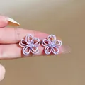 Detailaufnahme der violetten hohlen Blumenohrringe zur Größenreferenz an den Fingern - Hohle Blume (HE32264) / Gelb