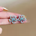 Nahaufnahme hellblauer hohler Blumenohrstecker mit feinen Emailledetails - Hohle Blume (HE32264) / Blau
