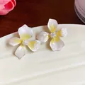 Detailed close-up of elegant flower earrings featuring white petals and yellow centers - Silver Earring Post Style / Yellow