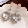 Close-up of vintage resin heart earrings with shimmering rhinestones and small pearls - Silver Earring Post-White