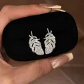 Detail of silver feather stud earrings with sparkling rhinestones in a display box - Feather Design / Silver
