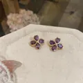 Elegante lila Zirkon Blumenstecker-Ohrringe mit Vergoldung auf beige Leinen-Stoff - Lila