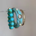 Primo piano di bracciale rigido in resina turchese con conchiglie e set di perline colorate. - Bracciale Resina + Bracciale Perline + Bracciale Metallo (HB6147) / Oro-Blu
