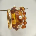 Dettaglio macro del set di braccialetti in resina ambrata con conchiglie e perle - Bracciale Resina + Bracciale Perline + Bracciale Metallo (HB6147) / Marrone oro